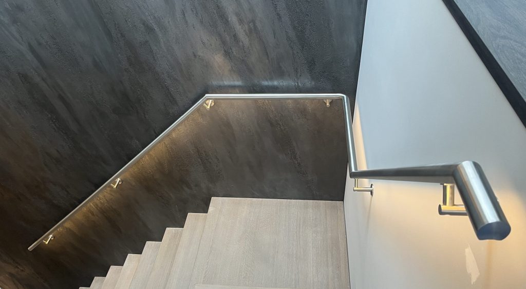 In de hoeken en vluchten verbonden RVS trapleuning met LED verlichting in een woning